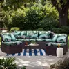 An outdoor sectional sofa with tropical-themed cushions is set up on a patio with a striped rug and a small coffee table. Náhled obrázku produktu