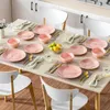 A dining table set with pink marble-patterned porcelain dishes, cutlery, napkins, and glasses, arranged for a meal. Produktbild-Vorschau