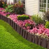 A garden bed bordered by a brown plastic fence with a wood-like texture, separating it from a green lawn. Náhled obrázku produktu