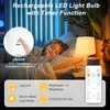 A child sleeping in bed next to a bedside lamp, with product features highlighted in overlays and a remote control shown. Produktbild-Vorschau