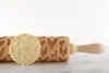 A wooden rolling pin with a chicken pattern and a cookie imprinted with the same pattern. Voir les images du produit