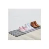 Shoes are arranged on a drying mat against a white brick wall. Náhled obrázku produktu