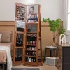A jewelry cabinet with a mirror and LED lights is shown in a bedroom setting next to a bed and a dresser. Voir les images du produit