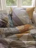 A close-up view of a bedding set with a geometric pattern, placed near a window. Produktbild-Vorschau