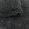 A close-up view of a dark gray shaggy rug. Produktbild-Vorschau