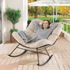 A woman relaxing in a beige rocking chair on a wooden deck with a garden view. Anteprima dell’immagine prodotto