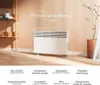 A white electric heater is shown in a room with a shelf and a plant. Produktbild-Vorschau