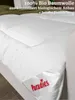 A white duvet is shown on a bed, with text overlay describing its features. Produktbild-Vorschau