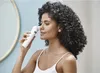 A woman is using a facial cleansing device on her face. Produktbild-Vorschau