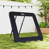 A black soccer rebounder net is set up on a green lawn in an outdoor setting, with a white wall and string lights in the background. Voir les images du produit