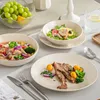 A table setting with various dishes including a salad, soup, and a meat dish, along with a bowl of grapes. Náhled obrázku produktu
