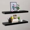 Two black floating shelves mounted on a light gray wall, decorated with various items. Náhľad obrázku produktu