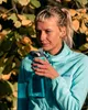 A woman drinking from a water bottle outdoors. Anteprima dell’immagine prodotto