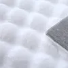 A close-up view of a white fluffy rug with a textured pattern and a grey backing visible on the right side. Produktbild-Vorschau