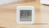 A small white digital thermometer and hygrometer sits on a wooden surface. Podgląd zdjęcia produktu