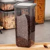 A clear shot of a transparent food storage container filled with coffee beans, placed on a wooden surface. Other similar containers are visible in the background. Náhľad obrázku produktu
