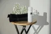 A white spray bottle and black towels are placed on a wooden stool. Produktbild-Vorschau