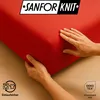 Hands are shown adjusting a red fabric, likely a bedsheet, with a logo and certifications visible. Produktbild-Vorschau