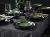A table setting with plates, bowls, glasses, and cutlery, arranged on a grey tablecloth. Náhľad obrázku produktu