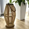 A wooden lantern with a glass insert sits on a wooden floor next to a white planter with a plant. Anteprima dell’immagine prodotto