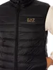 A man wearing a black puffer vest over a cream-colored hoodie. Produktbild-Vorschau
