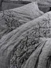 A close-up view of grey bedding with a black damask pattern. Produktbild-Vorschau
