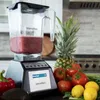 A Blendtec blender filled with a red smoothie, surrounded by fresh fruits and vegetables on a kitchen counter. Voir les images du produit