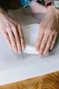 Hands are shown rolling a white material on a white surface. Podgląd zdjęcia produktu