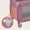 A close-up view of a pink travel crib, highlighting a side pocket with baby accessories inside. Anteprima dell’immagine prodotto
