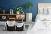 A bedroom scene with two ottomans in the foreground and a bed in the background. Produktbild-Vorschau