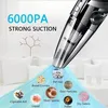 A handheld vacuum cleaner is shown with various types of debris it can clean up, such as pet hair, bread crumbs, dust particles, cigarette ash, mold spores, liquid, pollen, and dry debris. The text indicates "6000PA STRONG SUCTION." Produktbild-Vorschau
