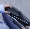 A person is placing a black electronic device into a gray bag containing a laptop. Voir les images du produit