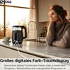 A woman is looking out a window in a kitchen, with a kettle on the counter. Produktbild-Vorschau