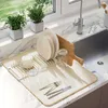 A kitchen sink area with a dish drying mat, dishes, glasses, and cutlery. Náhľad obrázku produktu