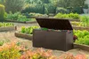 A brown storage box is open in a garden with raised garden beds filled with plants. Podgląd zdjęcia produktu