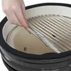 A hand is placing a grill grate into a ceramic kamado grill. Produktbild-Vorschau