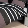 A close-up view of a striped duvet cover and pillow on a bed. Produktbild-Vorschau