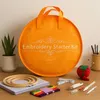 An embroidery starter kit is displayed on a wooden surface, with various accessories arranged around it. Náhled obrázku produktu