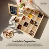 A wooden organizer box filled with scrunchies and other small items, next to a framed picture and flowers. Produktbild-Vorschau