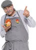 A man dressed as Meister Eder from Pumuckl, holding a Pumuckl figurine. Produktbild-Vorschau
