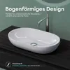 A white oval countertop sink with a chrome faucet is shown on a dark wood vanity. The background is a textured green wall. Produktbild-Vorschau