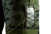 A close-up view of a camouflage work pant with a clear plastic pocket. Anteprima dell’immagine prodotto