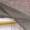 A close-up view of a fabric with a floral pattern, partially covered by a sheer gray fabric. Produktbild-Vorschau