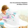 A child is looking at a toy sewing machine on a table. Produktbild-Vorschau