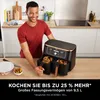 A man is smiling and holding a dual-zone air fryer in a kitchen setting. Produktbild-Vorschau