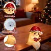 A Christmas-themed ghost statue night light is displayed on a wooden table in a festive living room setting with a Christmas tree in the background. Produktbild-Vorschau