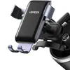 A close-up shot of a black and gray UGREEN gravity phone holder attached to a car's air vent. Náhled obrázku produktu