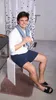 A man is sitting on a white stool in a bathroom, holding a towel around his neck. Produktbild-Vorschau