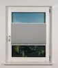 A window with a grey pleated blind partially covering the view of trees and sky. Produktbild-Vorschau