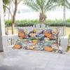 A swing bench with a colorful floral cushion is shown on a porch with a garden and water in the background. Voir les images du produit
